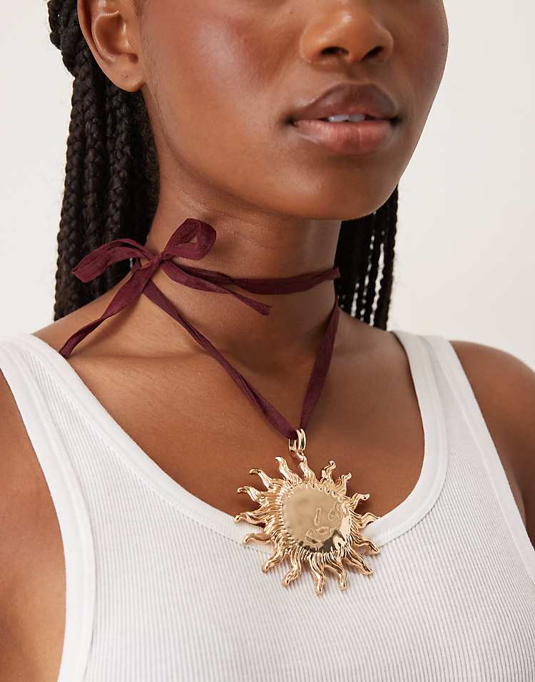 https://images.asos-media.com/products/asos-design-necklace-on-burgundy-ribbon-cord-with-large-sun-pendant-in-gold-tone/208789107-1-burgundyandgold?$n_750w$&wid=750&fit=constrain