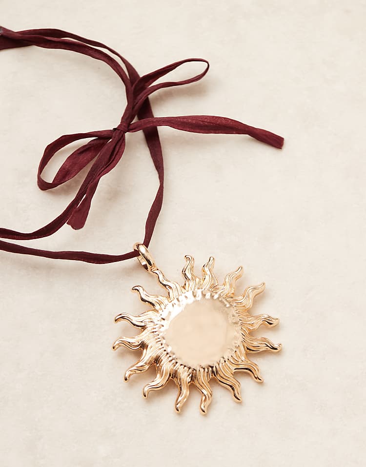 https://images.asos-media.com/products/asos-design-necklace-on-burgundy-ribbon-cord-with-large-sun-pendant-in-gold-tone/208789107-2?$n_750w$&wid=750&fit=constrain